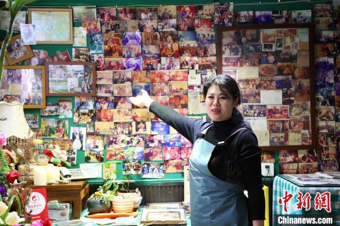 1月17日,苏蕊披萨店店主唐小琦介绍自己店里的照片墙.梁钦卿 摄