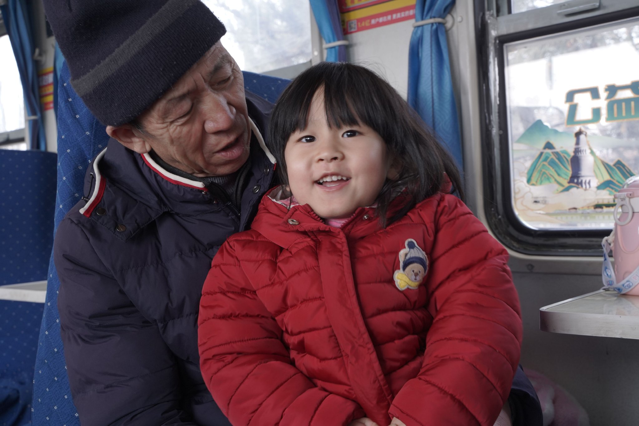 爷爷带着孙女乘坐8818次列车与儿子团聚。（申鹏飞 摄）