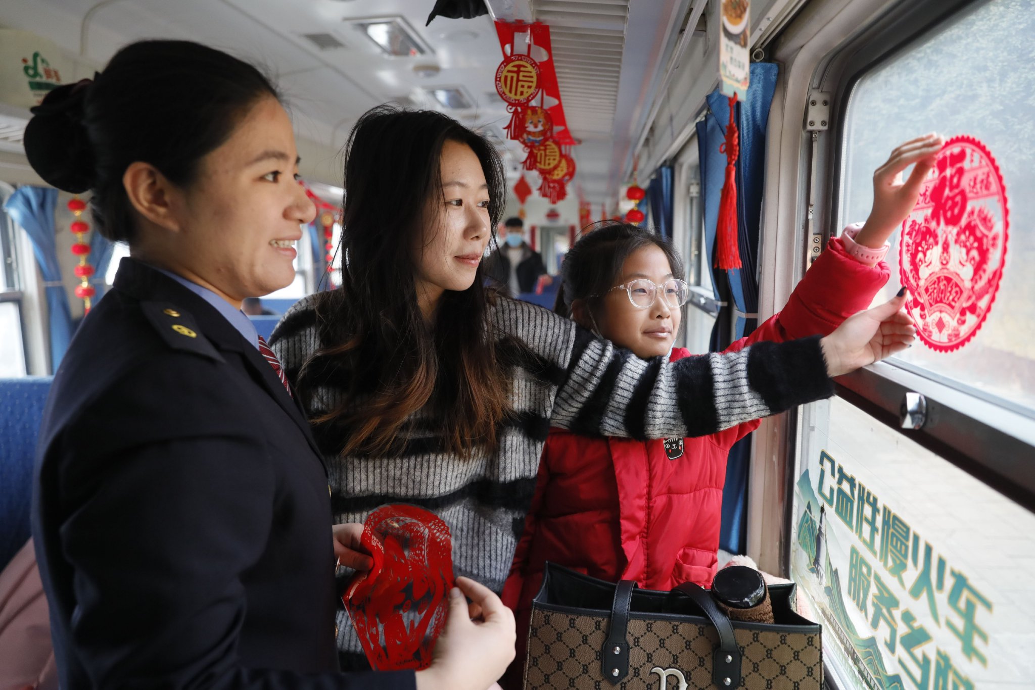 8818次列车工作人员与旅客共同装饰车厢喜迎新春。（张炯 摄）