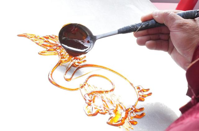 民间艺人在制作龙形糖画. 新华社 翁忻旸 摄