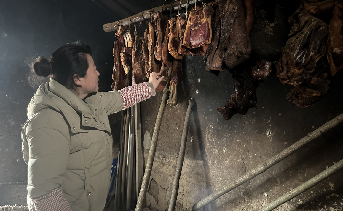 杨金秀查看自家腊肉熏制情况