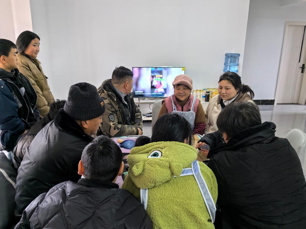 2月8日,受灾群众雷洪英一家围坐在取暖桌边取暖,看电视.(周洪 摄)