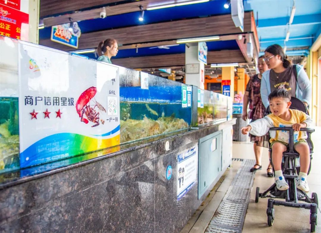 在位于三亚湾的龙兴海鲜广场海鲜销售及加工摊位前,均张贴"商户信用