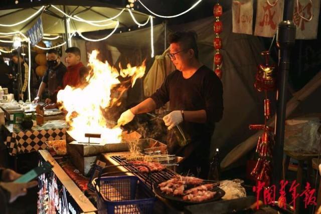 2月11日，重庆南滨路一处新春夜市，厨师正在烧烤摊位前做烤肉。中青报·中青网记者 陈剑／摄