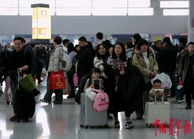 2月12日，重庆北站候车大厅，两个小朋友在大人的带领下推着行李。中青报·中青网记者 陈剑／摄