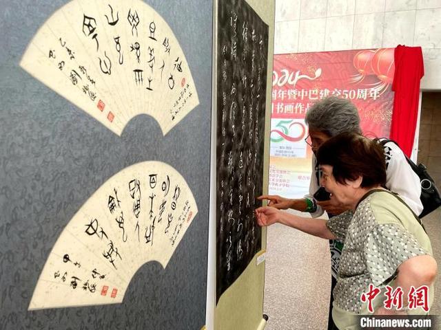 当地时间2月9日，巴西圣保罗，中国书画作品展上，两位老华侨正在研究书法作品。记者林春茵摄