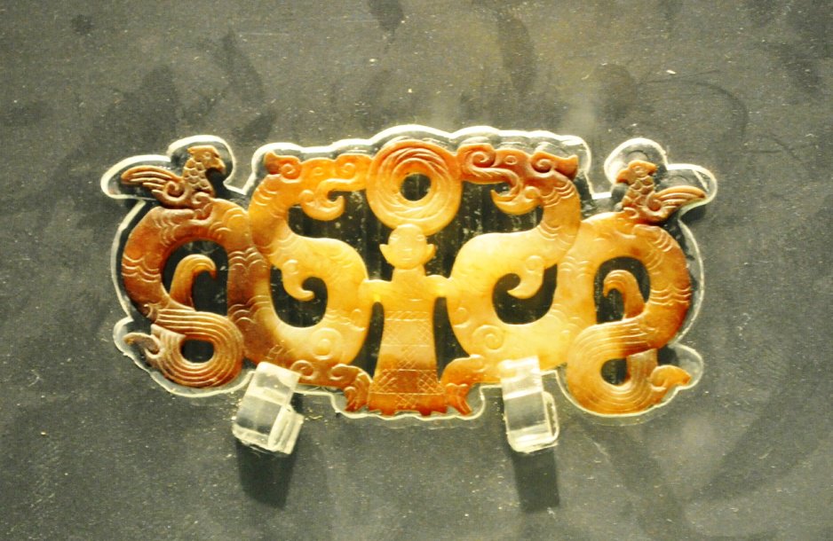 图为湖北荆州出土楚国玉佩:二龙拱璧,载人升天,摄于荆州博物馆,距今