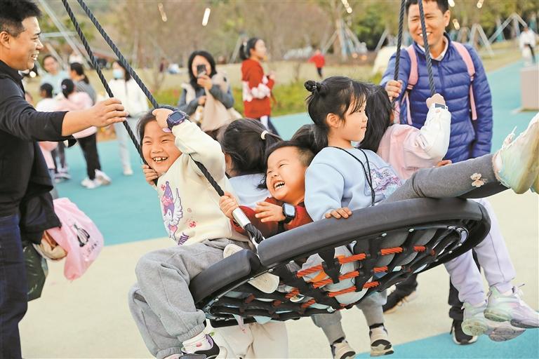 小朋友们在笔架山体育公园的游乐场里荡秋千.