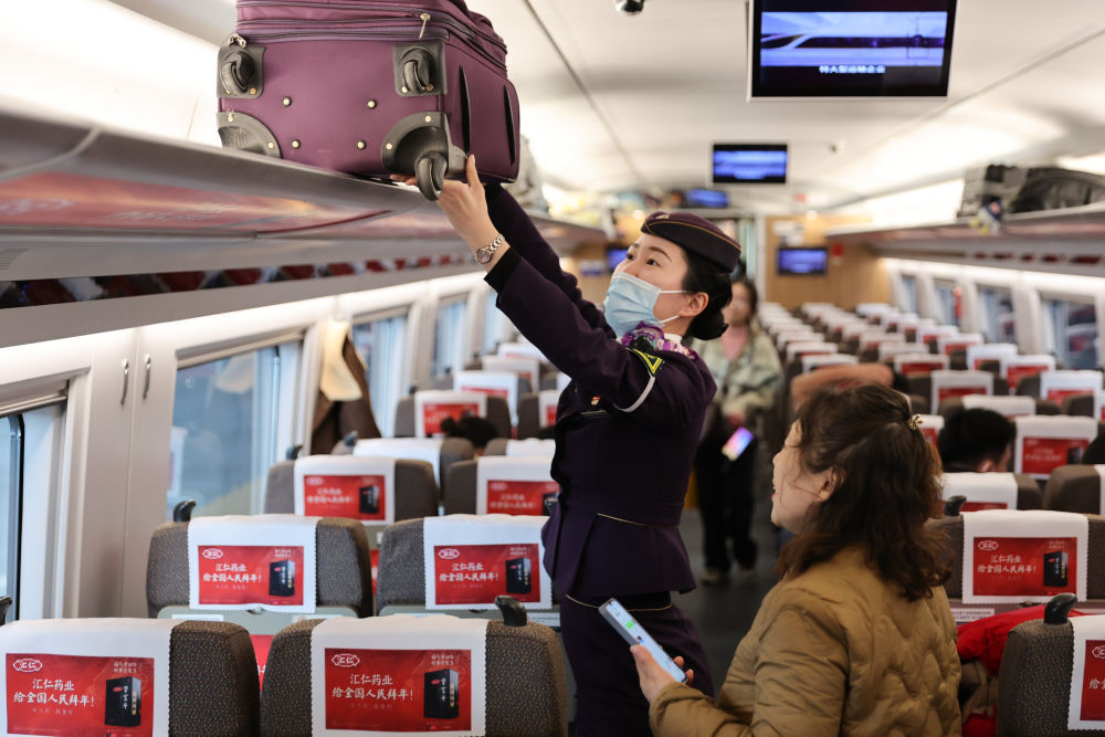2月17日,在上海虹桥站,乘务人员在车厢内帮助旅客放置行李.