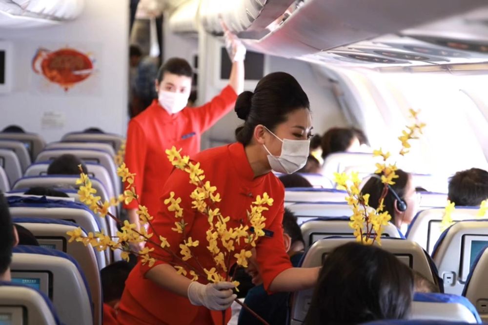南航新春主题航班上，乘务员为旅客发放迎春花。（南航供图）