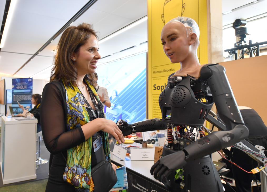 在瑞士日内瓦"人工智能造福人类全球峰会"上,一名参会者与仿真机器人