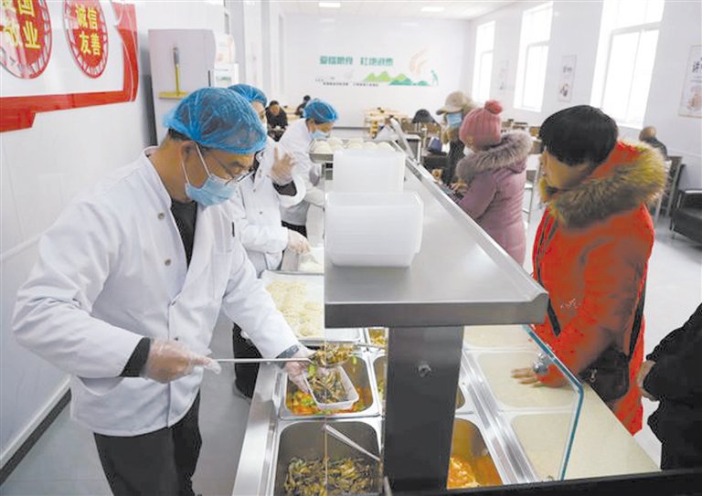 居民在涿州双塔街道永济秀园小区内的便民食堂排队打饭.