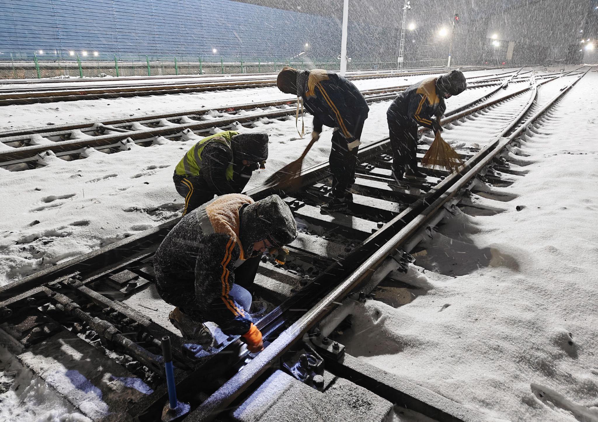 图为中铁三局运输分公司员工连夜在铁道道岔等关键部位破冰除雪