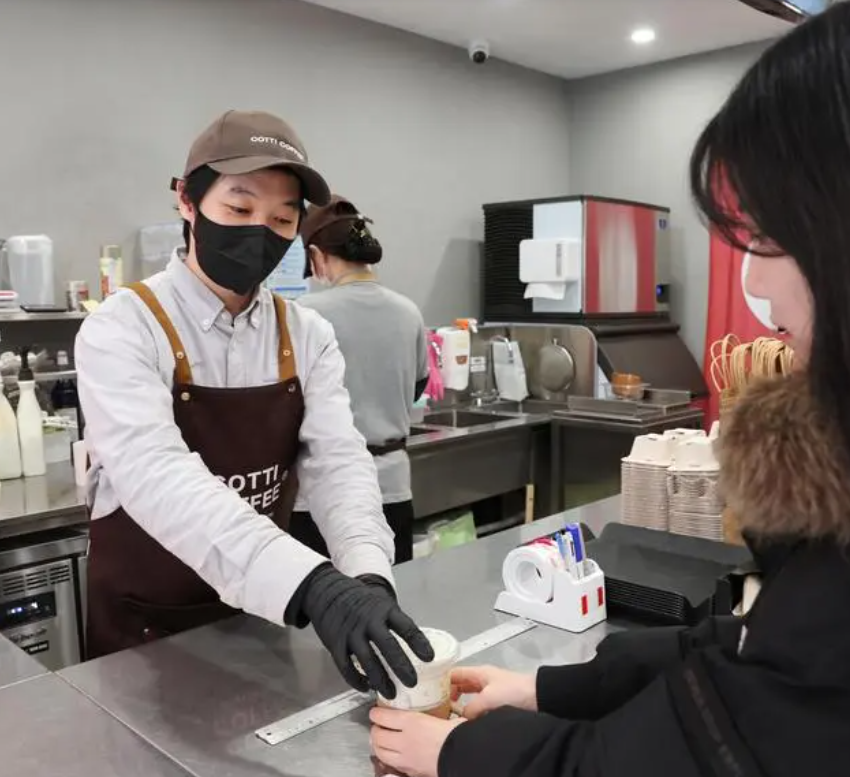 上图为一名顾客在印度尼西亚雅加达一家中国品牌咖啡店外排队等待.