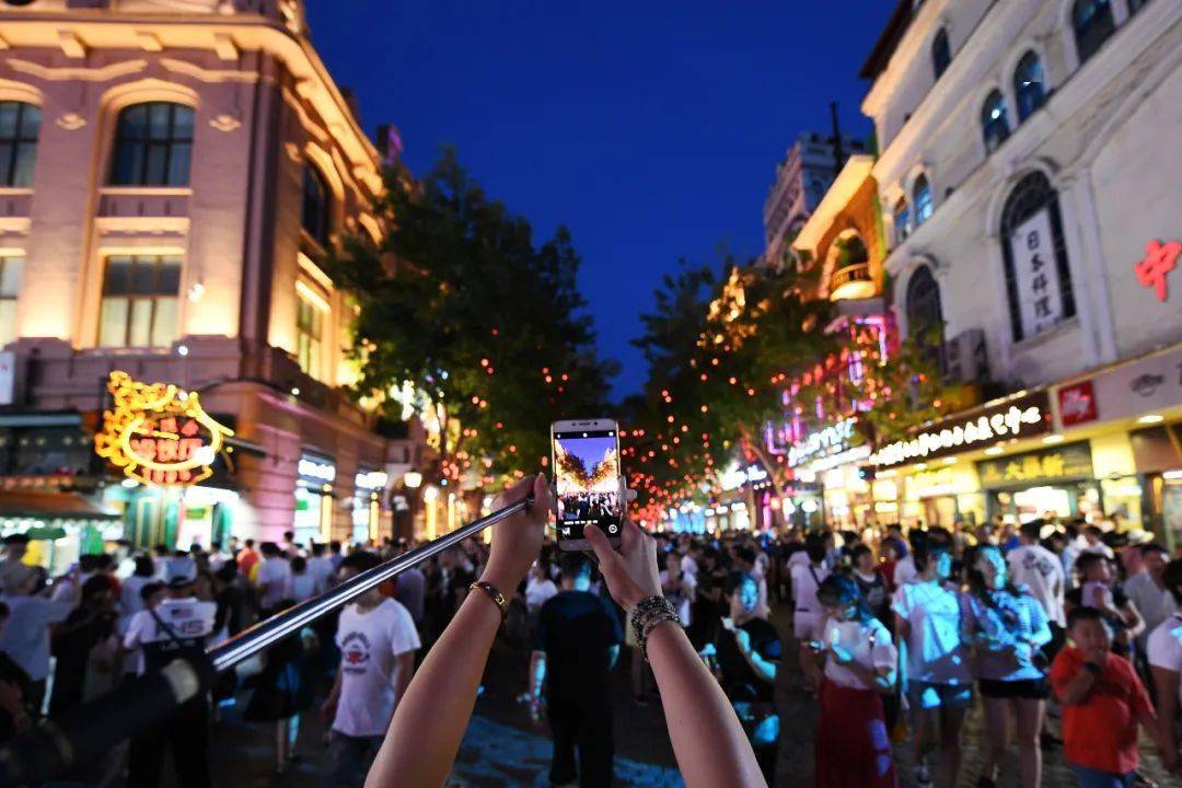 一位游客用手机拍摄夜色中的哈尔滨中央大街（2023年8月1日摄）。新华社记者 王建威 摄