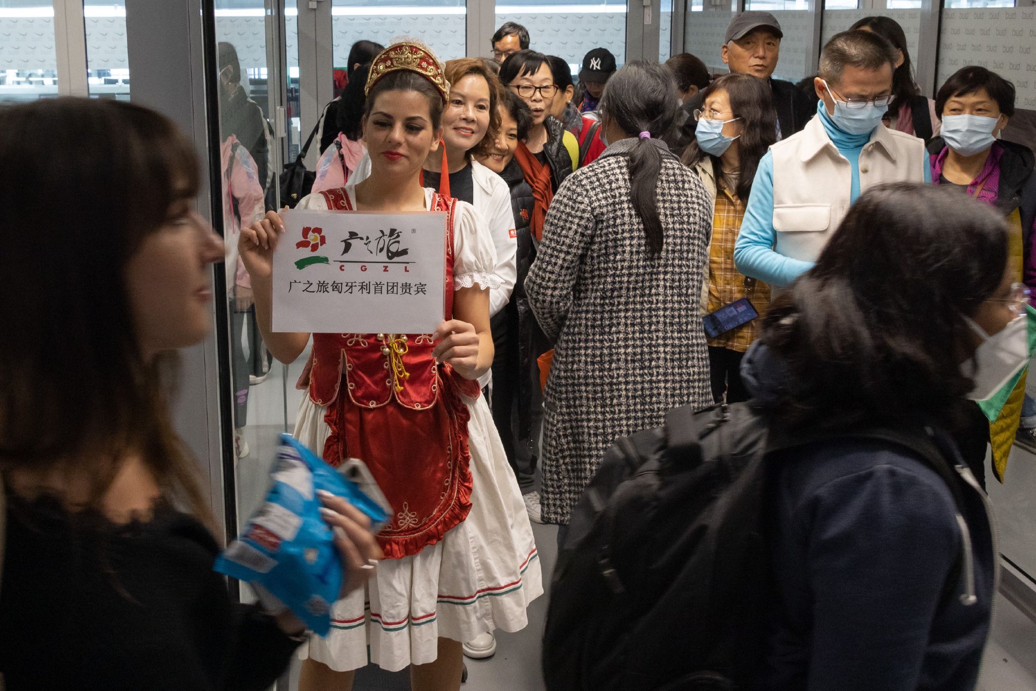 3月26日，在匈牙利布达佩斯机场，一名女士身穿匈牙利民族服装欢迎中国游客到来 图片来源：新华社