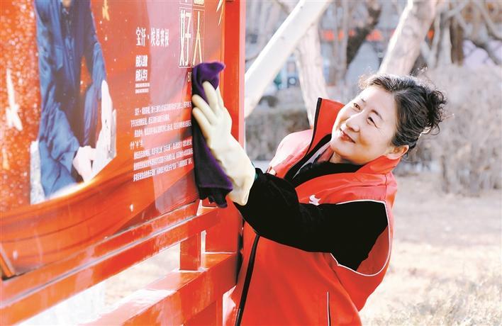 的学雷锋志愿服务活动中,大营房社区的一名巾帼志愿者在擦拭宣传板