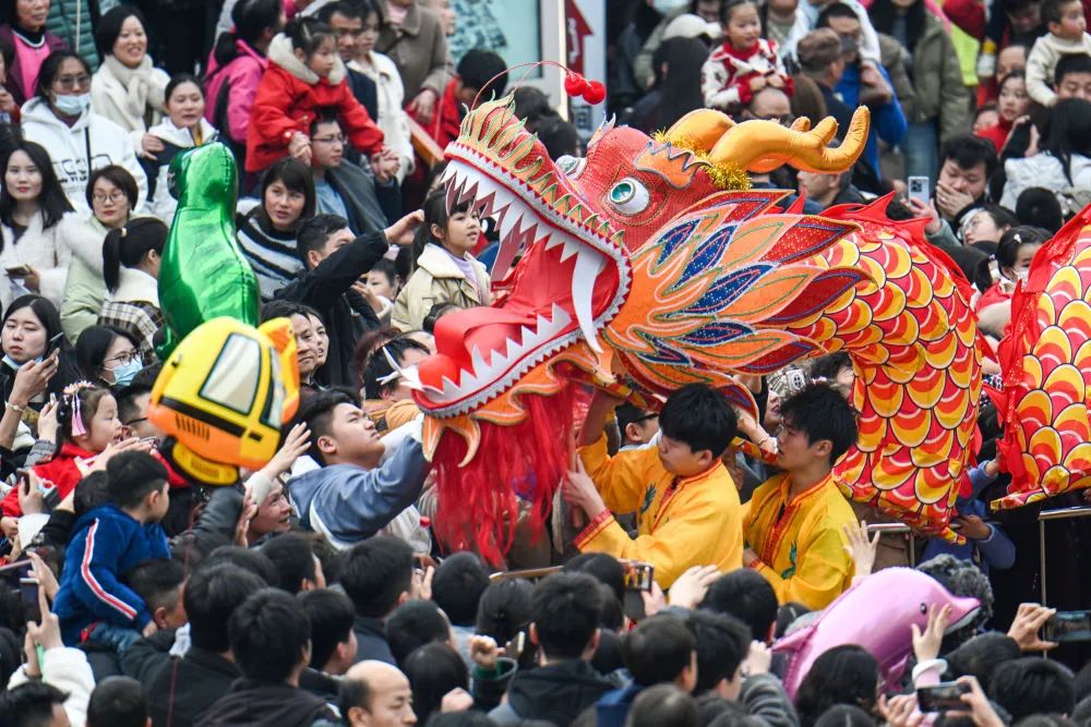 2月12日,在南昌市西湖区万寿宫历史文化街区,游客与板凳龙演员互动.