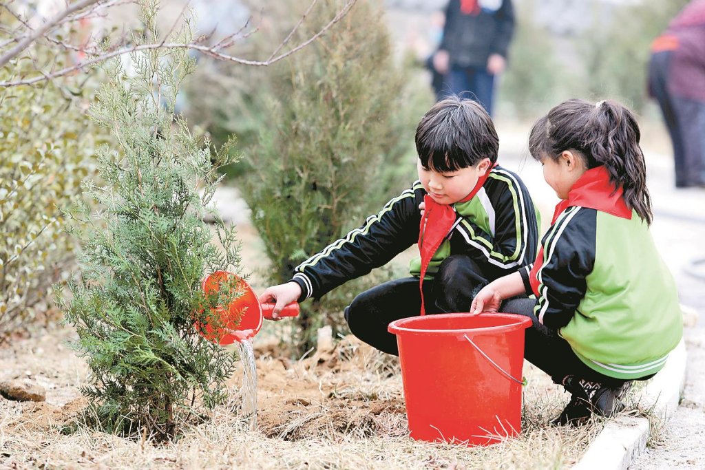 参加义务植树活动的学生为树苗浇水
