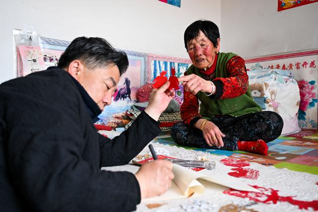 3月15日,段建珺(左)在和林格尔县羊群沟乡记录当地老人梁巧连的剪纸