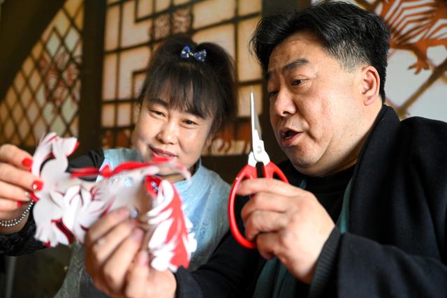 段建珺(右)在和林格尔剪纸传习所内与徒弟牛春霞交流剪纸技艺(3月14日