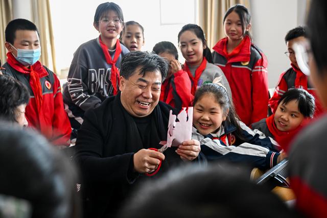 3月14日,段建珺(中)在和林格尔县第二小学向小学生讲解剪纸技艺.