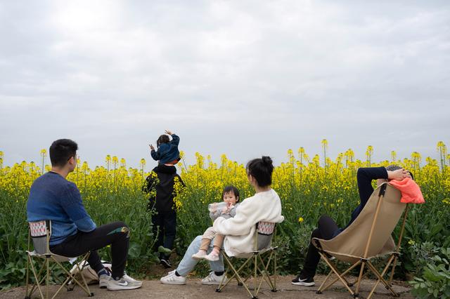 3月17日,在四川省绵阳市安州区秀水镇,来自绵阳市的游客在油菜花田边小憩。新华社记者 江宏景 摄