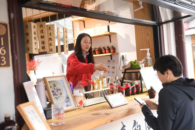 2月20日，在绍兴市越城区仓桥直街，一家黄酒创意饮品店的店主在指导顾客下单。新华社记者 翁忻旸 摄