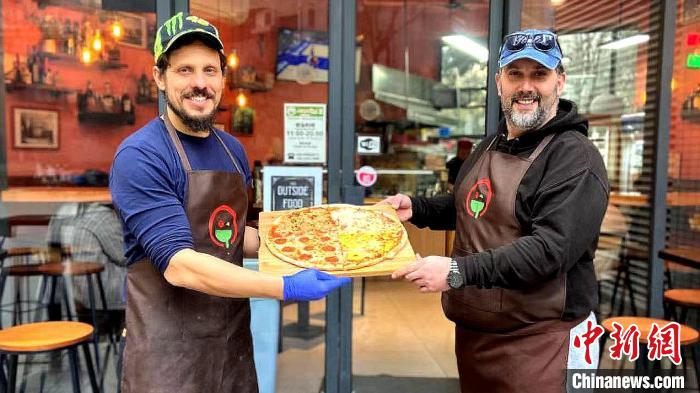 2024年3月,史荣茂(右)与博瑞(左)在店门前展示披萨.(受访者供图)