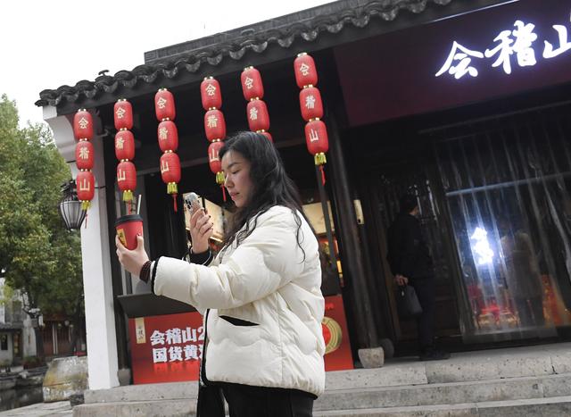 2月20日，一名游客在绍兴市越城区黄酒小镇拍摄刚刚购买的黄酒奶茶。新华社记者 翁忻旸 摄