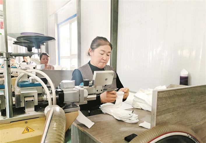 阿克陶县唐锦纺织"家庭工坊"员工讲解袜子定型注意事项(摄于3月14日)
