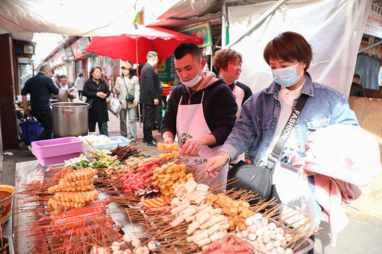 3月19日,游客在天水市秦州区的一麻辣烫摊位前选取菜品.