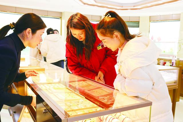 图片说明: 3月,在浙江湖州的一家商场内,两位顾客在挑选黄金饰品.