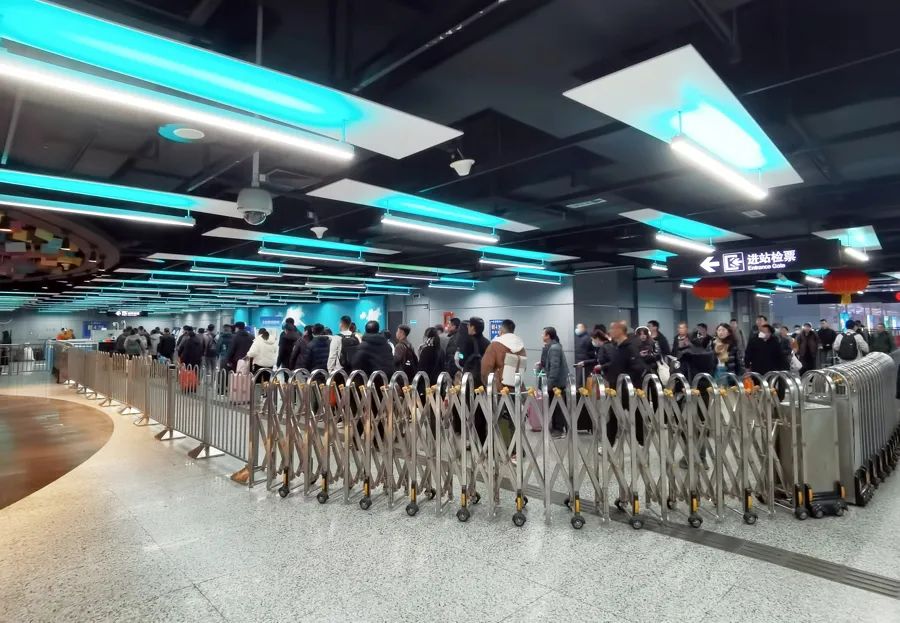 △图为今年春运期间，上海火车站的到站乘客换乘地铁三四号线时，等待安检进入地铁站的乘客队伍排起“长龙”。