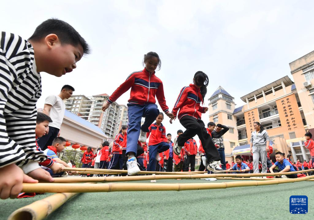3月26日,在梧州市长洲区新兴二路小学,同学们在课间练习跳竹竿舞.