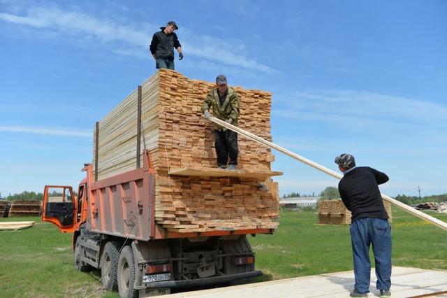 资料图片：俄罗斯鄂木斯克州阿季尔卡村木材加工车间的工人将制成品搬到车上准备运走（俄新社）