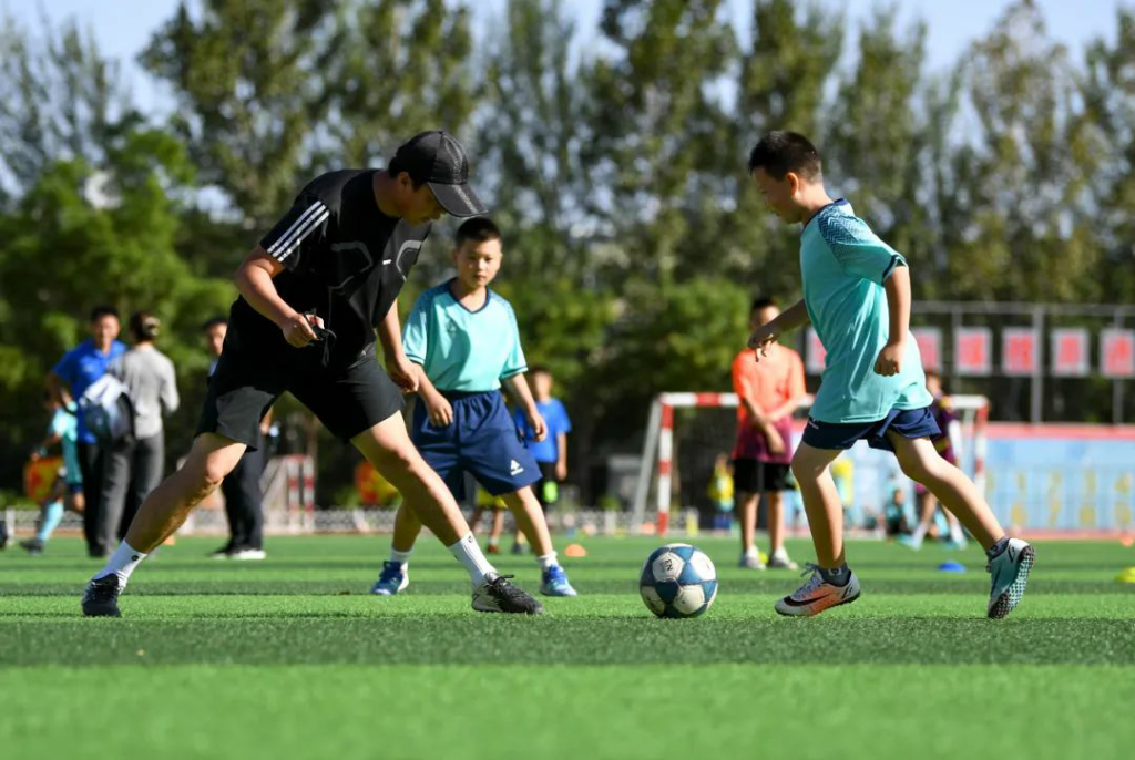 ↑教练指导小学生开展足球训练。图据新华社