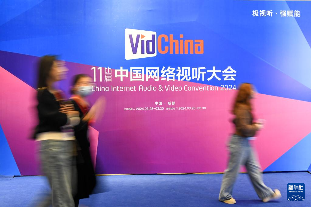 　　  3月28日，参会者从第十一届中国网络视听大会开幕式会场外的展板前走过。新华社记者 唐文豪 摄