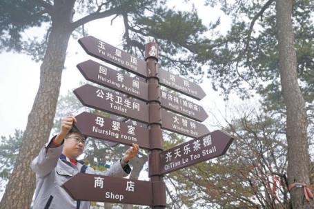 妙峰山景区工作人员调整新安装的标识 牌，为 游客做好路线指引。
