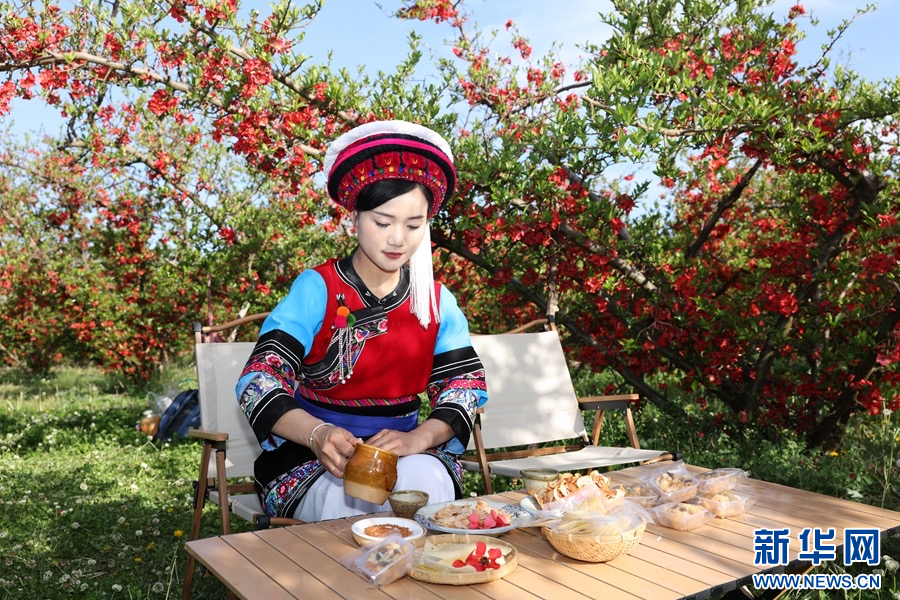 身着白族服饰的“金花”在木瓜园中为游客准备茶饮和特色美食（摄于3月26日）。新华网发（赵勇 摄）