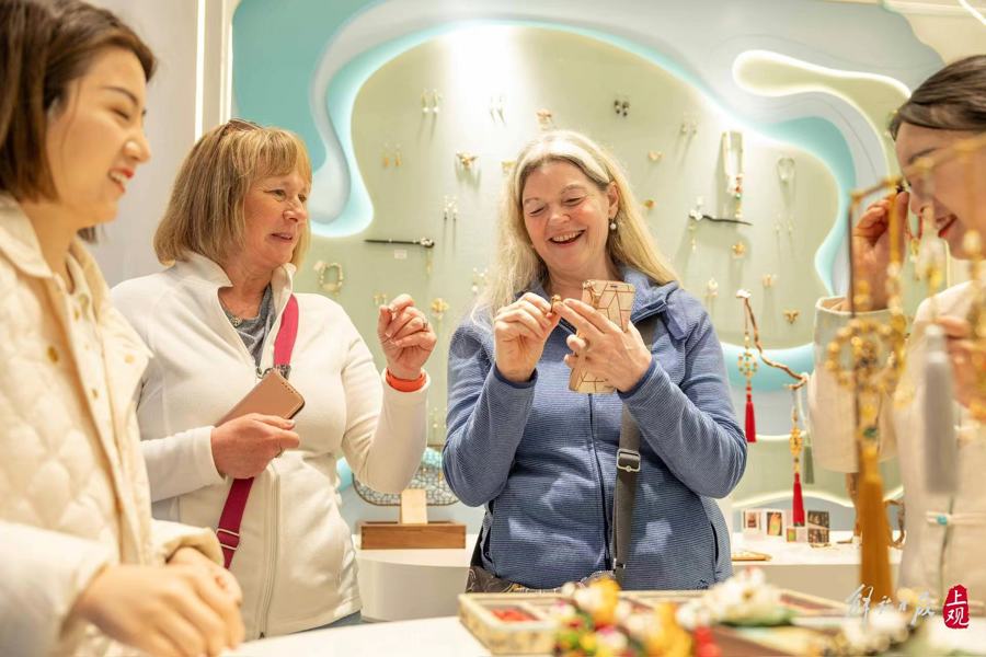 海外游客在商铺试戴首饰,笑逐颜开.