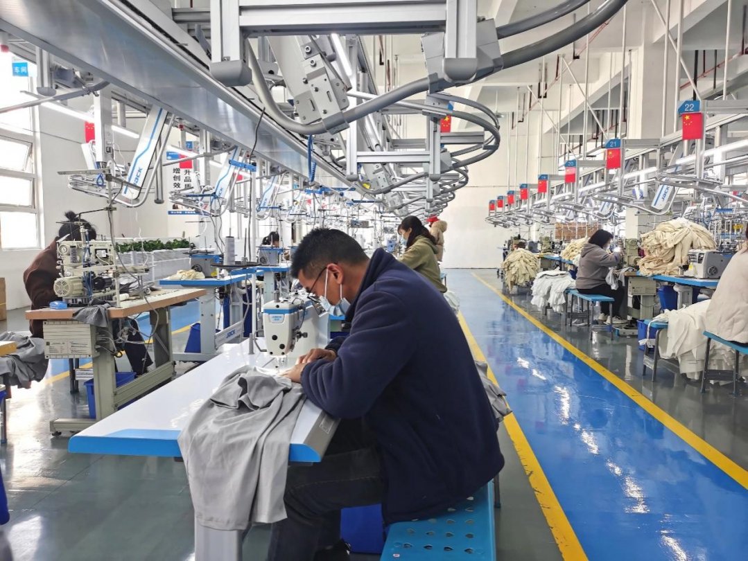 图为都匀市绿茵湖产业园区蒂菲尔服饰有限公司生产车间，工人们在缝纫机上忙个不停。 