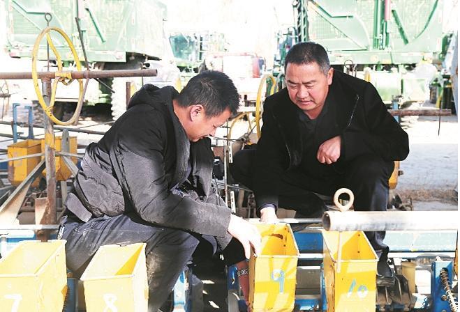 在铁门关市丰诚农机专业合作社,陈昆(右)和社员一起检修农机具(资料