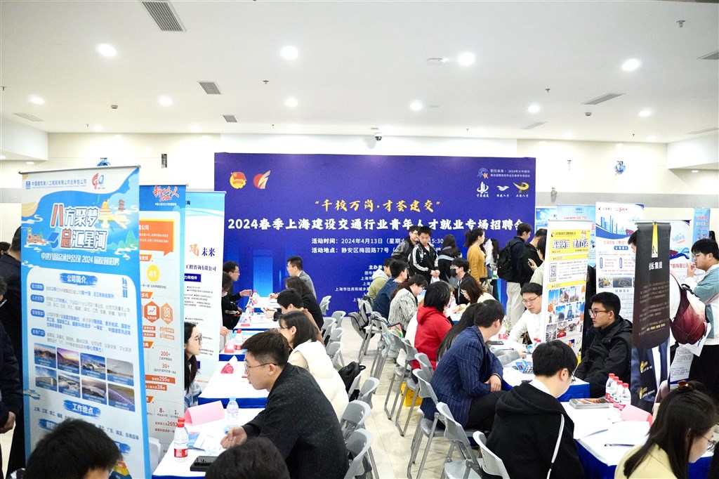 在招聘会现场,人头攒动,求职者们手持简历,穿梭于各个企业的招聘摊位