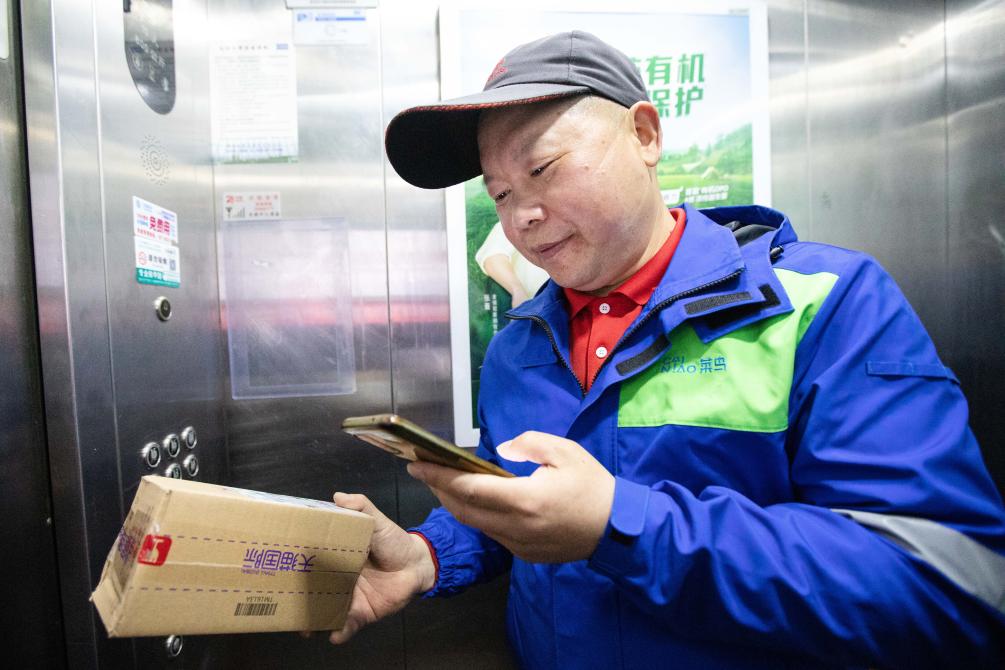　　3月29日，杭州菜鸟速递快递员姜荣成在确认消费者送货上门要求后，正在上门配送。（受访者供图）