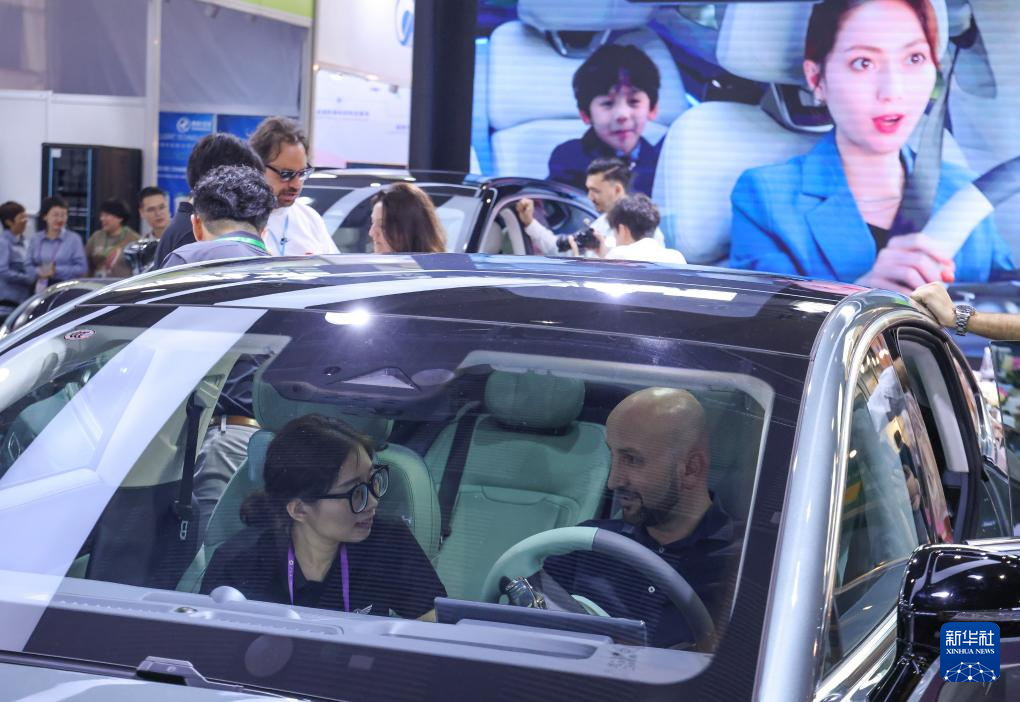 4月15日，广交会上一名采购商在展台工作人员介绍下了解中国新能源汽车。新华社记者 刘大伟 摄