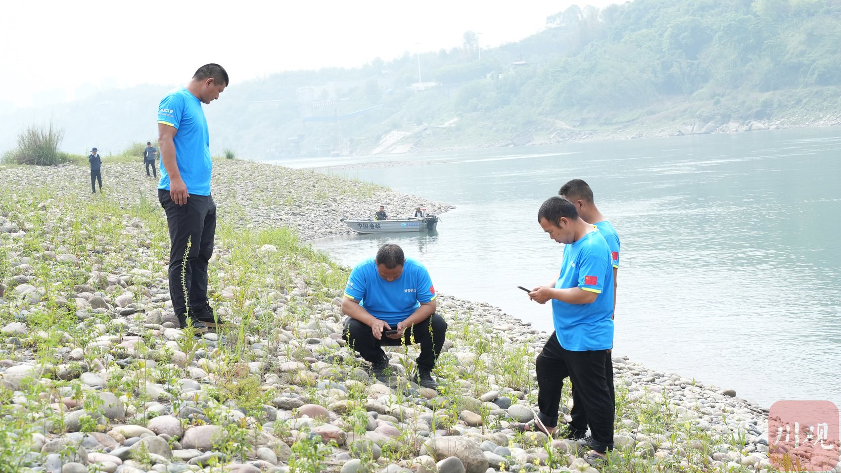 周涛（中）与巡护队员一起记录沿江湿地的植物生长情况。
