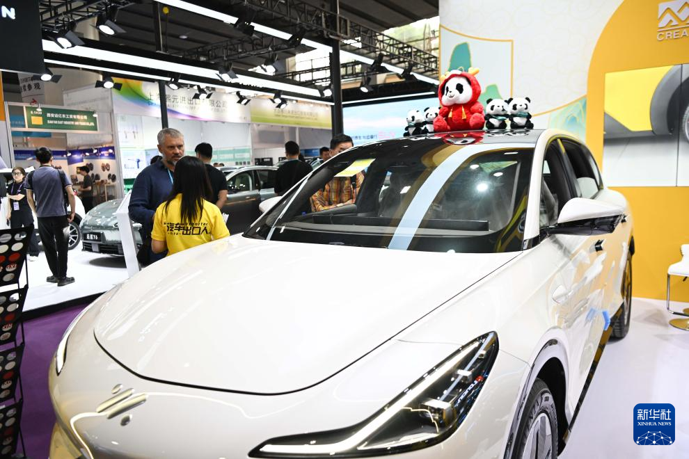 4月15日，在第135届广交会的一家新能源汽车出口企业展台，采购商在洽谈业务。新华社记者 邓华 摄