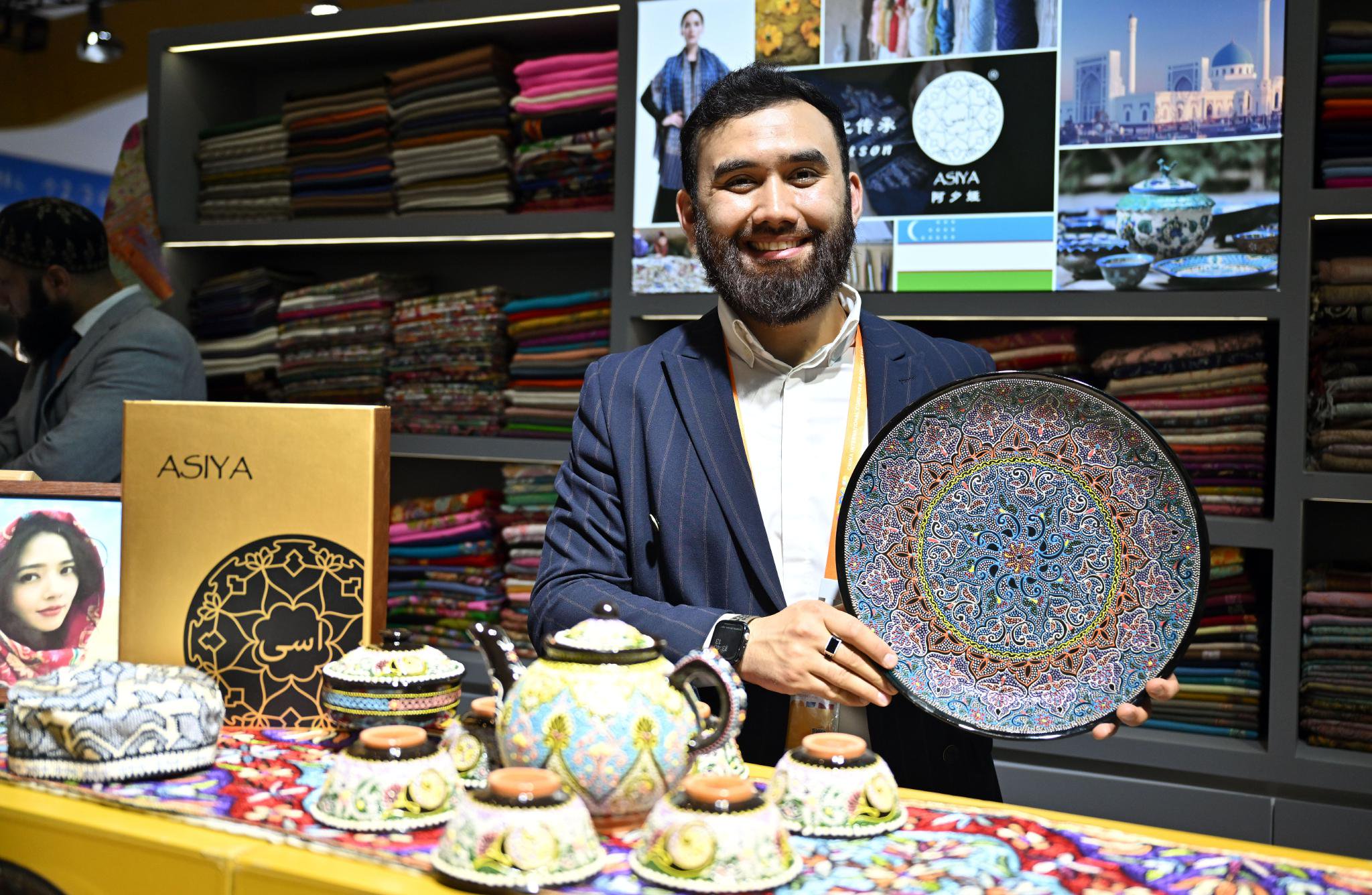 4月13日，一名乌兹别克斯坦展商在展示手工陶瓷盘。 新华社记者 郭程 摄