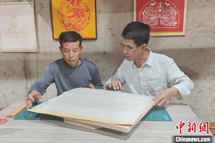 15日，林长聪(右)和伙伴一起设计、创作刻纸作品《猛虎下山》。吴冠标 摄